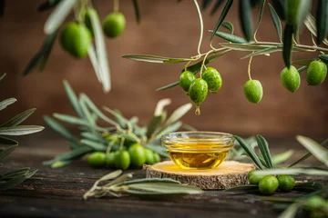Fotobehang Onderzeeër Small glass bowl filled with olive oil placed on wooden surface surrounded by fresh green olives and olive branches. Concept of Mediterranean cuisine, organic farming, healthy food and natural harvest  © petrrgoskov