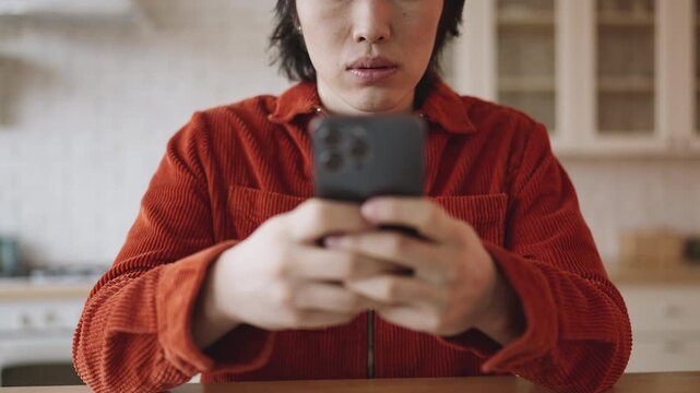 Young Asian man texting on smartphone and reading comments in social network