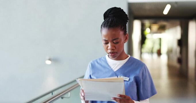 Documents, healthcare and walking with nurse black woman in hospital for planning or research. File, medical and reading with African person in clinic hallway for insurance or review of information