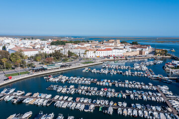 Obraz premium Faro in Algarve shows a busy dock with many boats. The old town stands in the background, showcasing typical architecture and clear blue skies