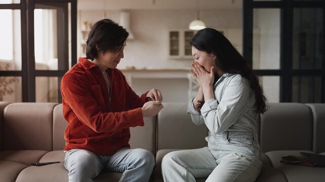 Asian woman accepting boyfriend's marriage proposal, putting ring on finger