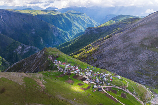 Aerial view of a quaint village nestled on the slope, its houses a splash of color against the vast green and brown mountains, Lukomir, Federation of Bosnia and Herzegovina, Bosnia and Herzegovina.