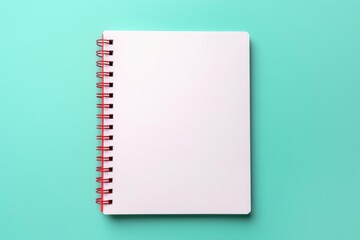 Empty spiral notebook laying on colorful teal desk surface, ready for writing
