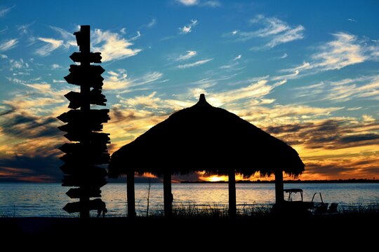 A brilliant sunset glows against the silhouette of a tiki hut