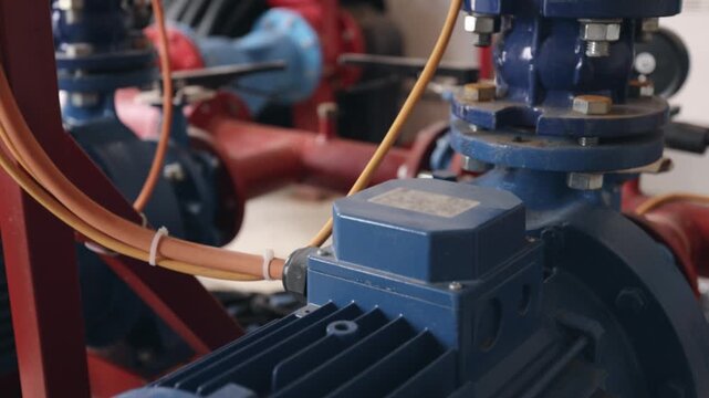 Electric motor, Motor drive, Control panel. Detailed view blue electric motor with connected cables, part larger mechanical system in industrial facility.