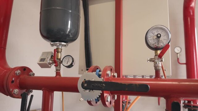 Pressure control, Valve assembly, Industrial plumbing. Close-up industrial pressure control system featuring gauges, valves, and expansion tank on red pipeline network.