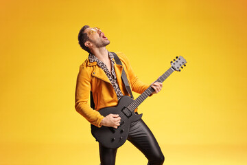 Energetic male rock musician playing electric guitar and singing