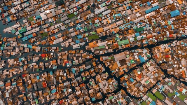 Aerial view of a sprawling network of buildings with colorful roofs amidst dark waterways, creating a textured, vibrant scene, Lagos, Lagos, Nigeria.