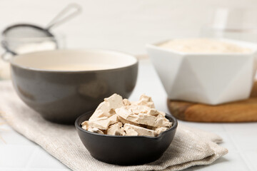 Fototapeta premium Yeast and dough on white tiled table, closeup