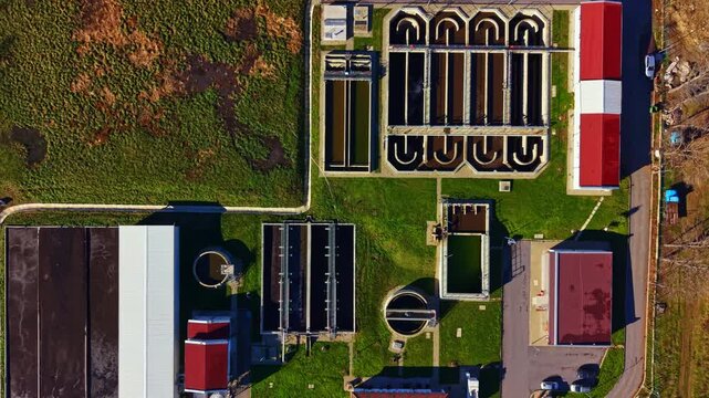 Aerial view of a water treatment facility showing multiple tanks and structures. The scene is busy with different sections working on water purification processes.