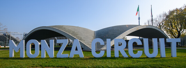 Obraz premium Iconic Monza Circuit entrance with modern curved architecture and bold signage, captured on a sunny day in Italy, symbolizing speed, motorsport heritage, and innovation.