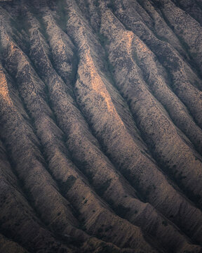 Aerial view of the dramatically furrowed earth, carved by time and erosion into stark ridges and shadowy valleys, Bromo, East Java, Indonesia.