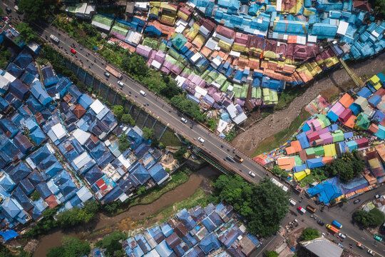 Aerial view of vibrant rooftops creating a patchwork of color split by a bridge and river, a dazzling display of urban artistry, Malang, East Java, Indonesia.