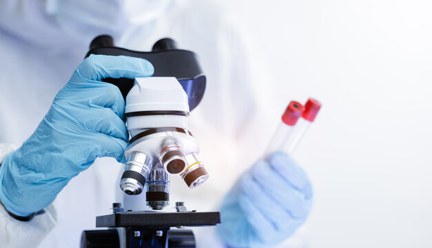 Banner Scientist in lab coat analyzing samples with microscope and test tubes