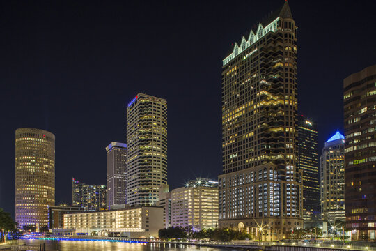 View of shimmering city lights reflecting on the dark water amidst towering buildings under a twilight sky, Tampa, Florida, United States.