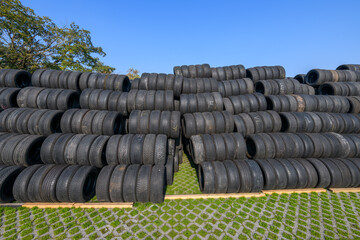 Obraz premium Stacked racing tires forming a safety barrier at Monza racetrack, Italy, under a clear blue sky, conveying speed, motorsport intensity, and track-side atmosphere.
