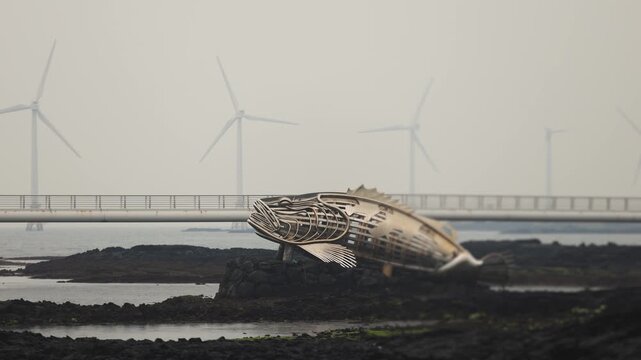 Jeju Island, Jeju-Do, South Korea,  Sinchang Windmill Coastal Road landscape, line of wind mills power generators along the coast, offshore wind farm energy turbines, aerial drone view, green energy
