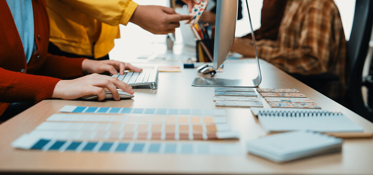A vibrant workspace shows creative professionals actively collaborating, sharing color samples, and engaging in a productive design process at a modern office desk setup. SACTR