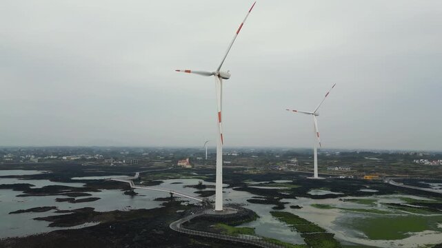Jeju Island, Jeju-Do, South Korea,  Sinchang Windmill Coastal Road landscape, line of wind mills power generators along the coast, offshore wind farm energy turbines, aerial drone view, green energy