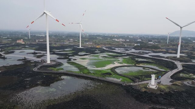 Jeju Island, Jeju-Do, South Korea,  Sinchang Windmill Coastal Road landscape, line of wind mills power generators along the coast, offshore wind farm energy turbines, aerial drone view, green energy