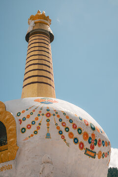 View of the striking white stupa adorned with colorful circular patterns against a clear blue sky, Phobjikha Valley, Wangdue Phodrang, Bhutan.