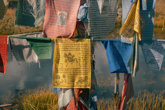 View of vibrant prayer flags fluttering against the serene backdrop of a tranquil river, creating a peaceful scene, Phobjikha Valley, Wangdue Phodrang, Bhutan.