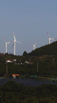 Jeju Island, Jeju-Do, South Korea,  Sinchang Windmill Coastal Road landscape, line of wind mills power generators along the coast, offshore wind farm energy turbines, aerial drone view, green energy