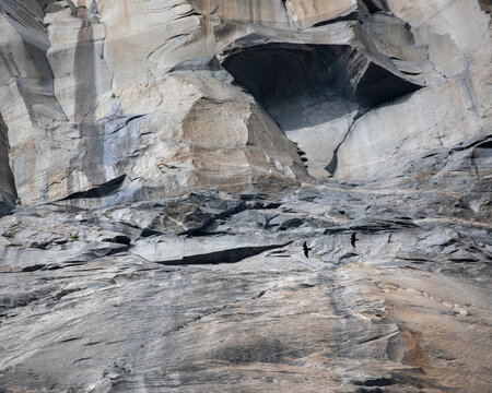 View of a massive, textured granite cliff face, streaked with shadows and light, creating a dramatic, natural canvas, Yosemite Valley, California, United States.