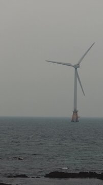 Jeju Island, Jeju-Do, South Korea,  Sinchang Windmill Coastal Road landscape, line of wind mills power generators along the coast, offshore wind farm energy turbines, aerial drone view, green energy