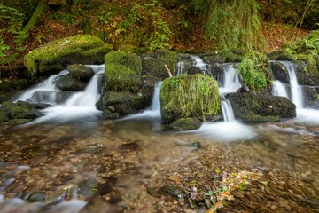 Obraz premium Long exposure of a waterfall on the Hoar Oak Water river at Watersmeet in Exmoor National Park