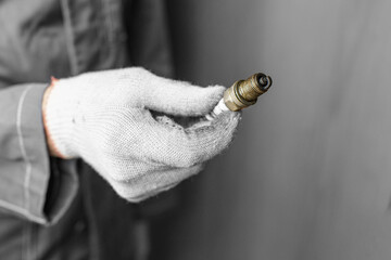 A mechanic holds old spark plugs. Defective spark plugs, stained with motor oil. Soot on the spark plugs.