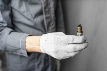 A mechanic holds old spark plugs. Defective spark plugs, stained with motor oil. Soot on the spark plugs.