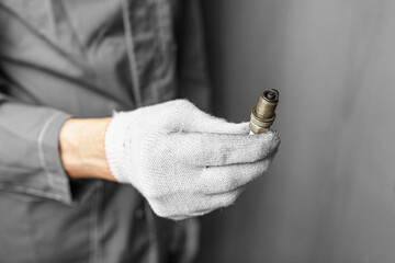 A mechanic holds old spark plugs. Defective spark plugs, stained with motor oil. Soot on the spark plugs.
