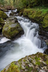 Obraz premium Long exposure of a waterfall on the East Lyn river flowing through the woods at Watersmeet in Exmoor National Park
