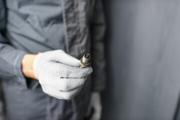 A mechanic holds old spark plugs. Defective spark plugs, stained with motor oil. Soot on the spark plugs.