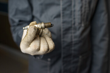 A mechanic holds old spark plugs. Defective spark plugs, stained with motor oil. Soot on the spark plugs.