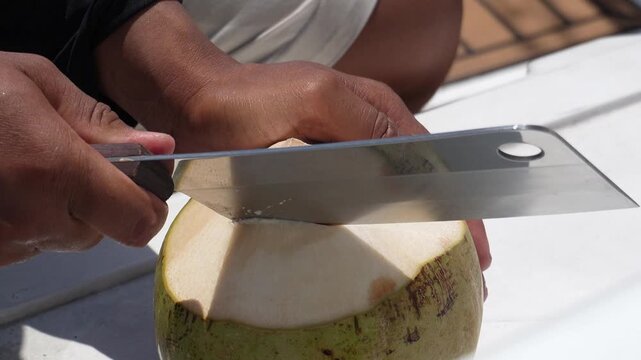 Opening a coconut. Opening a coconut with a large cleaver on a yacht, close-up shot
