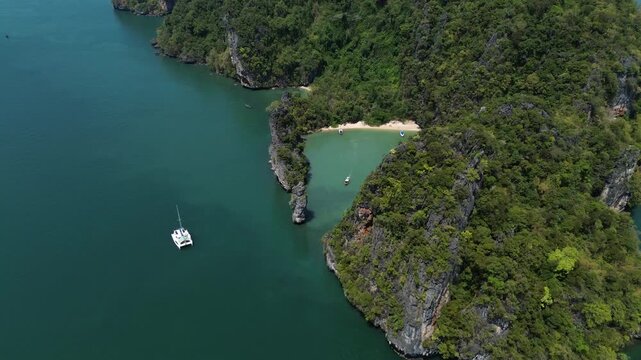 Sailing trips. Sailing yacht off Panak Island, yacht trip in Thailand. Drone view of a sailing catamaran off the coast of a limestone island.