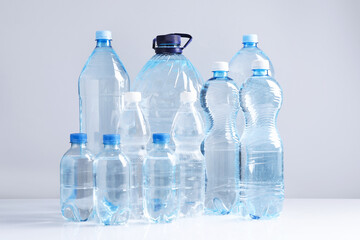 Water bottles of different sizes on white table against grey background