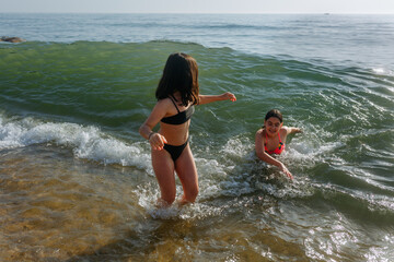 Fototapeta premium two girls playing with waves on the sandy beach