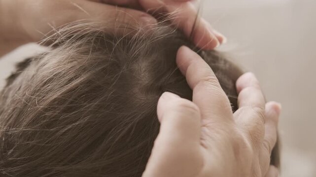 Close-up child's head with female hands searching for lice and nits in hair, regular hygiene and pest control, Pediculosis