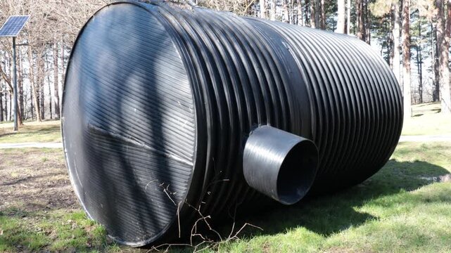 Large Black Corrugated Plastic Water Tank Installed Outdoors in Garden