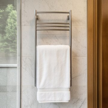 Fluffy white towel on a chrome towel warmer, against a marble wall, offering a clean and luxurious bathroom aesthetic. Towel warmer, bathroom decor