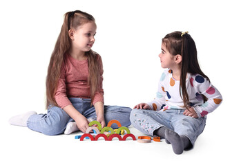 Fototapeta premium Cute little girls playing with colorful wooden pieces on white background