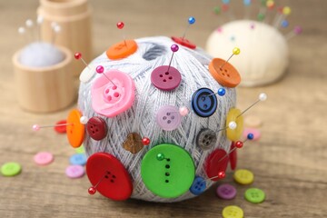 Naklejka premium Skein of yarn with buttons and pins on wooden table, closeup