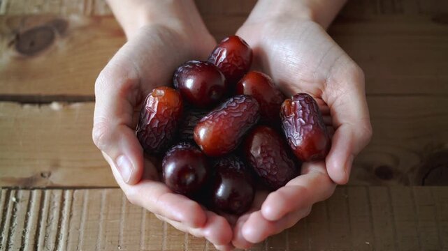 Hands holding a generous portion of fresh dates on a rustic wooden background image photo