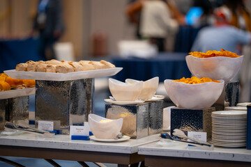 Various dishes served on plates at a buffet table, offering a wide selection of food for guests. Catering setup with assorted meals prepared for self-service dining at an event or restaurant