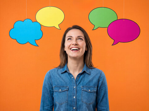 Smiling woman looking at colorful empty speech bubbles for communication concept