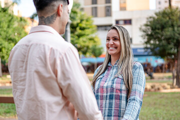 Fototapeta premium Happy young woman smiling while looking at her partner during a romantic date in a city park.