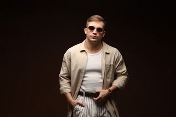 Obraz premium Fashion model. Handsome man in sunglasses posing against black background